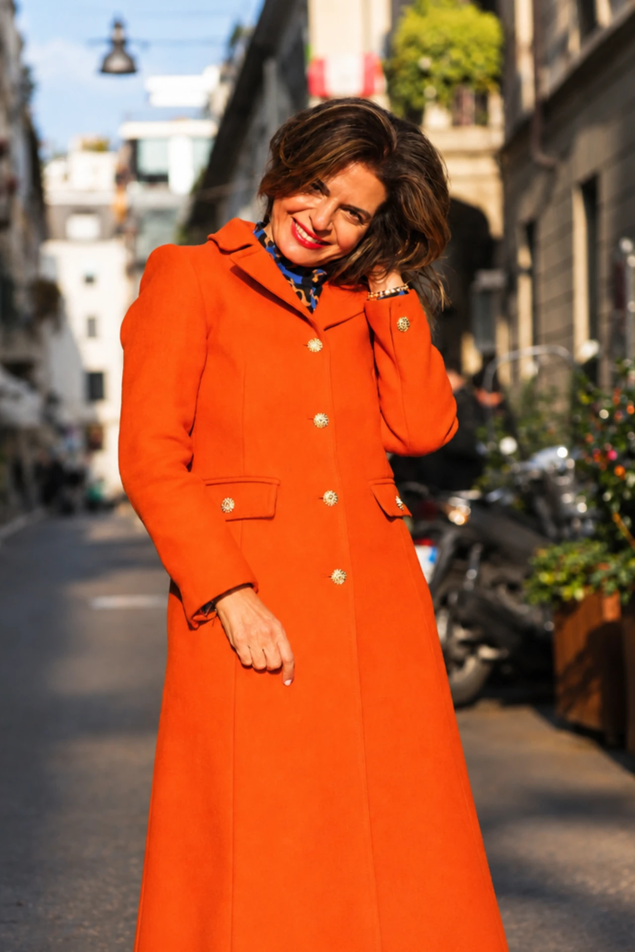 Sima Azadegan wearing an orange coat on a city street